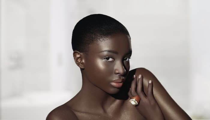Femme à la peau noire, nuque et épaule dégagées, sur fond clair Image
